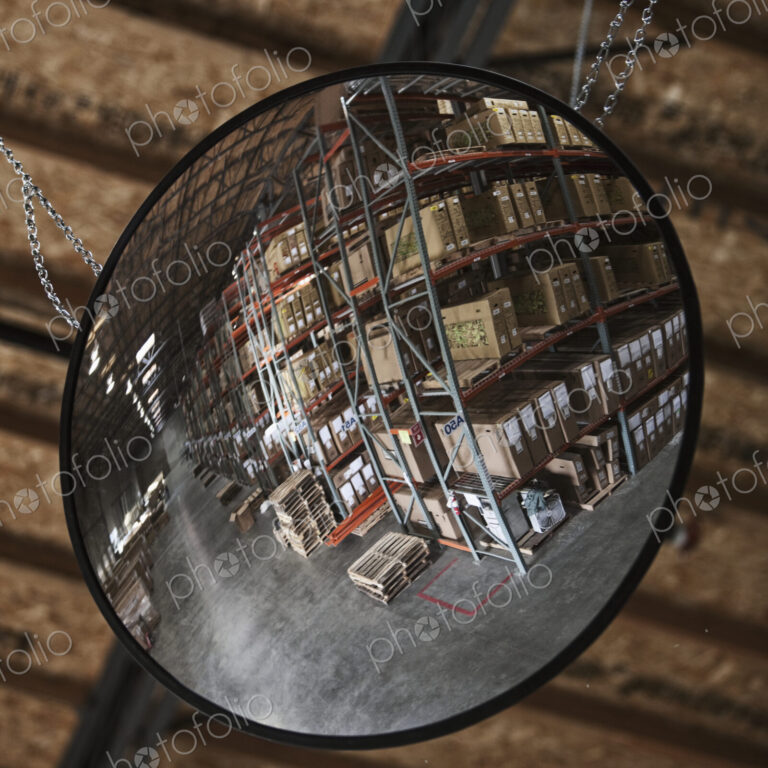 Cardboard boxes on shelves in warehouse reflected in mirror