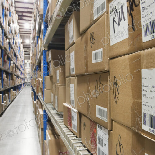 Cardboard boxes on tall shelves in warehouse.