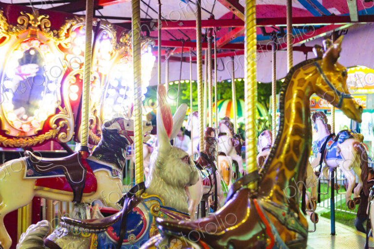 Carousel ride at an amusement park, with carousel horses giraffes and a rabbit.