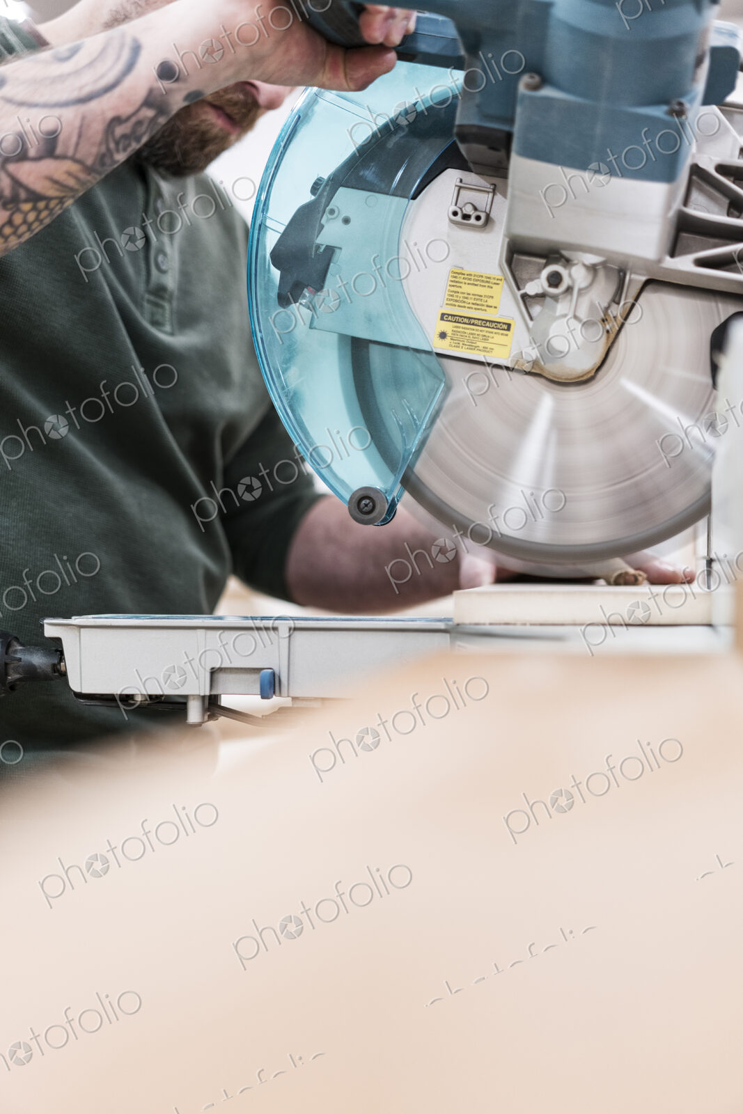 Carpenter using a radial saw to cut a wooden board in a woodworking factory.