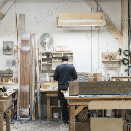 Carpenter working on a cabinet project at his work station in a furniture factory.