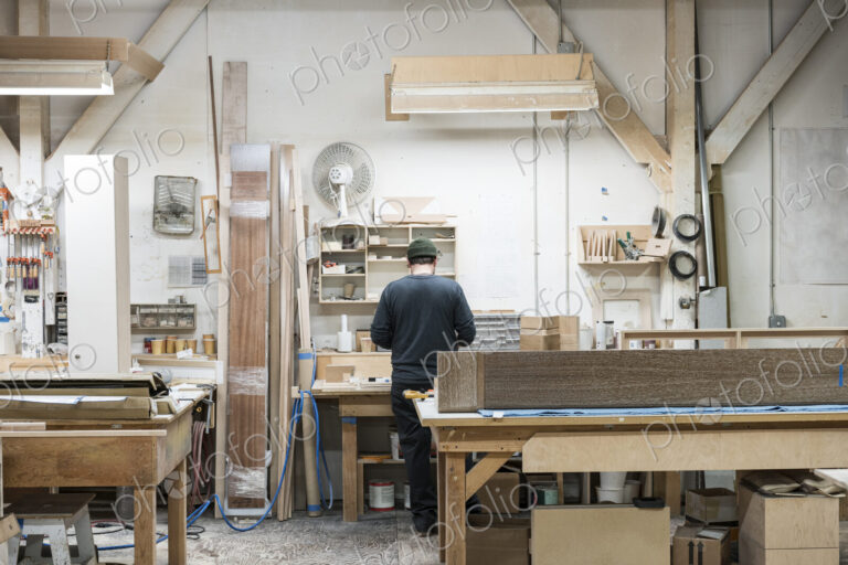 Carpenter working on a cabinet project at his work station in a furniture factory.
