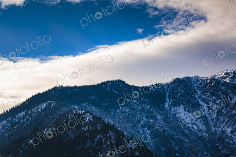 Cascade Mountains rising above Leavenworth, low cloud and a blue sky patch.