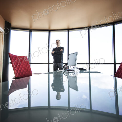 Casually dressed caucasian businessman relaxed at his reflective desk in front of a… Casually dressed caucasian businessman relaxed at his reflective desk in front of a…