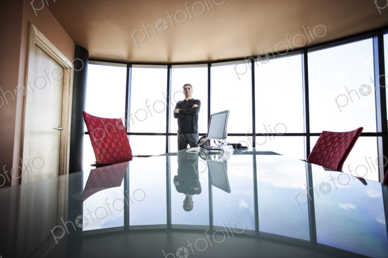 Casually dressed caucasian businessman relaxed at his reflective desk in front of a…