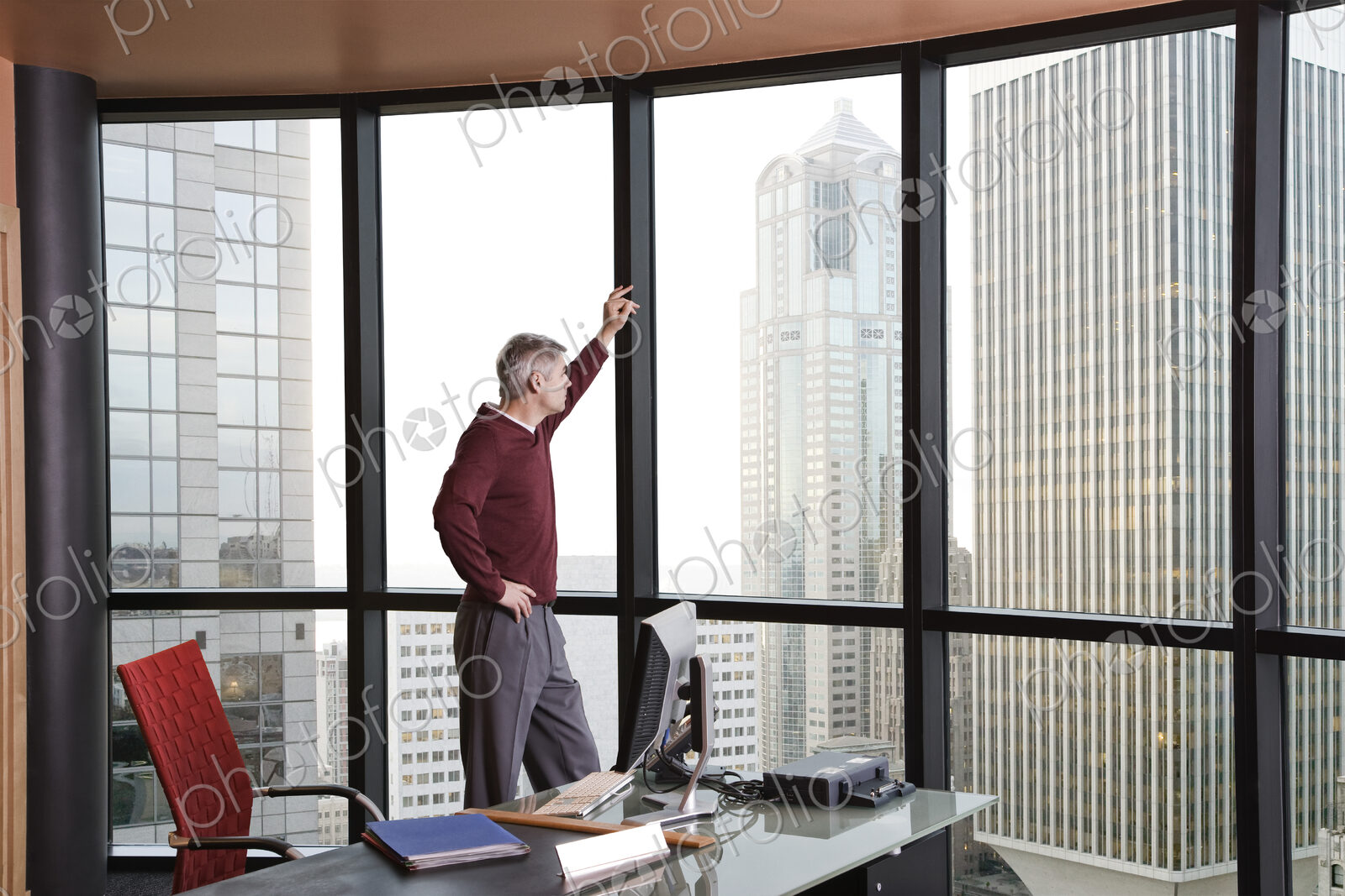Casually dressed caucasian businessman standing and looking at a skyline out an office…