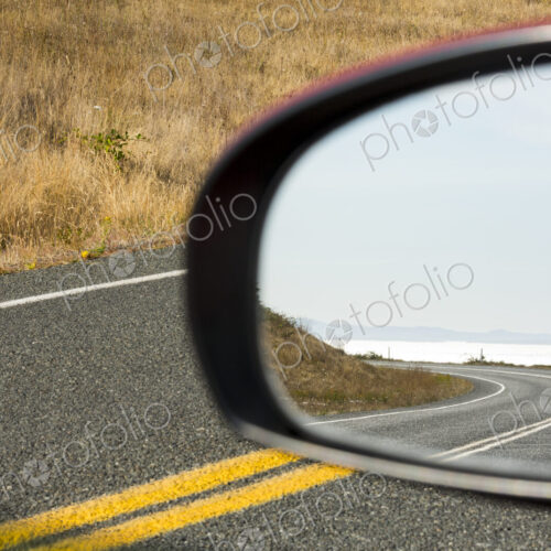 Cattle Pass Road, a curving road along the coast, view in the rear view mirror. Cattle Pass Road, a curving road along the coast, view in the rear view mirror.