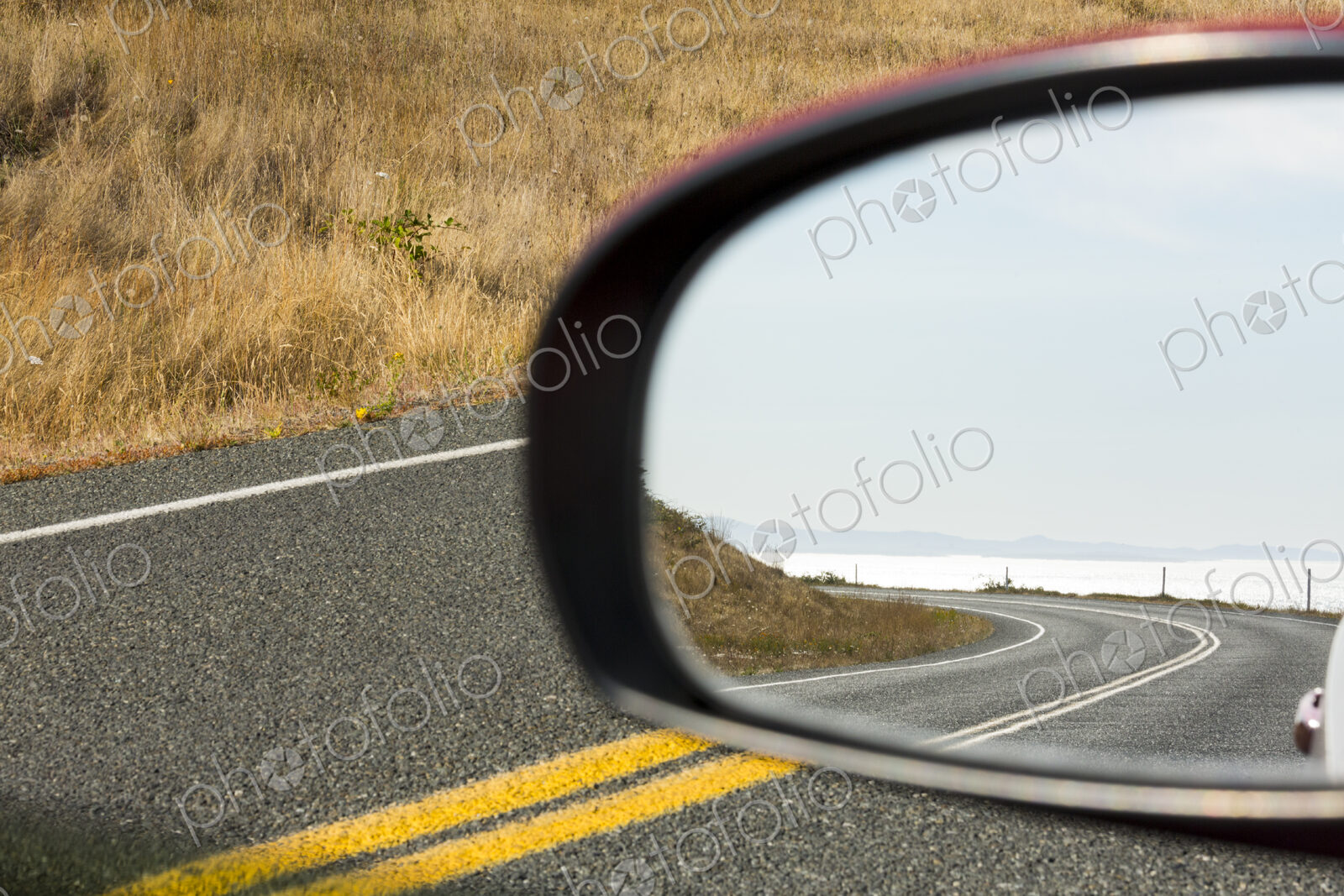 Cattle Pass Road, a curving road along the coast, view in the rear view mirror.