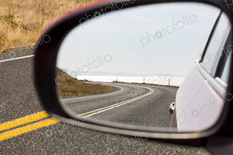 Cattle Pass Road, a curving road along the coast, view in the rear view mirror.