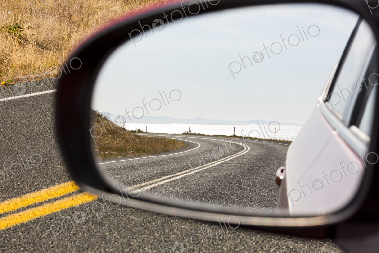 Cattle Pass Road, a curving road along the coast, view in the rear view mirror.