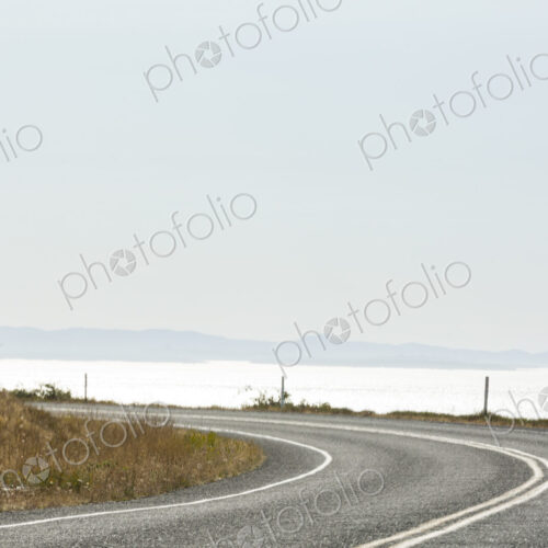 Cattle Pass Road, a curving road along the coast, view over the water. Cattle Pass Road, a curving road along the coast, view over the water.