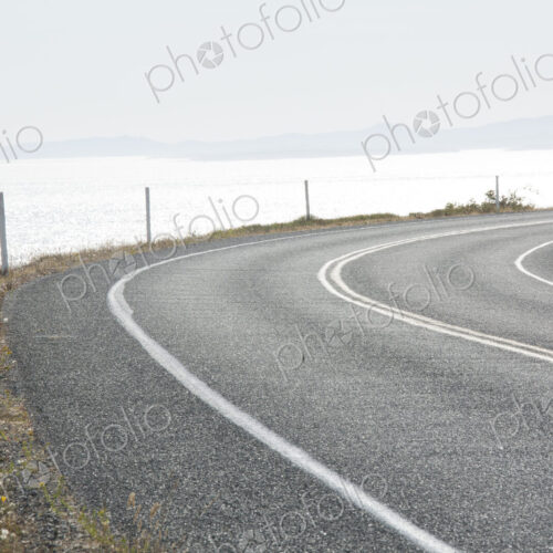 Cattle Pass Road, a curving road along the coast, view over the water. Cattle Pass Road, a curving road along the coast, view over the water.
