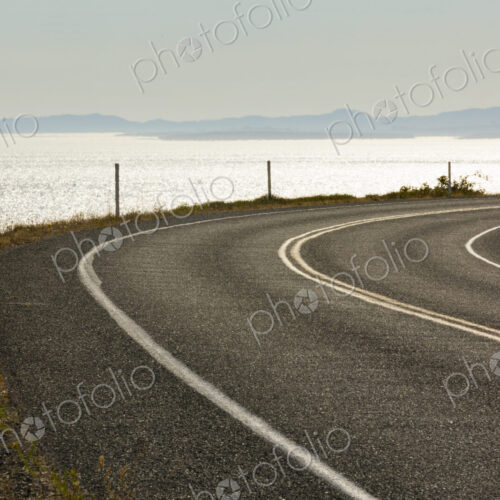 Cattle Pass Road, a curving road along the coast, view over the water. Cattle Pass Road, a curving road along the coast, view over the water.