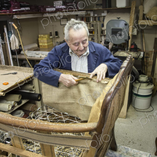 Caucaisan senior male upholsterer working on a chair in his garage shop. Caucaisan senior male upholsterer working on a chair in his garage shop.