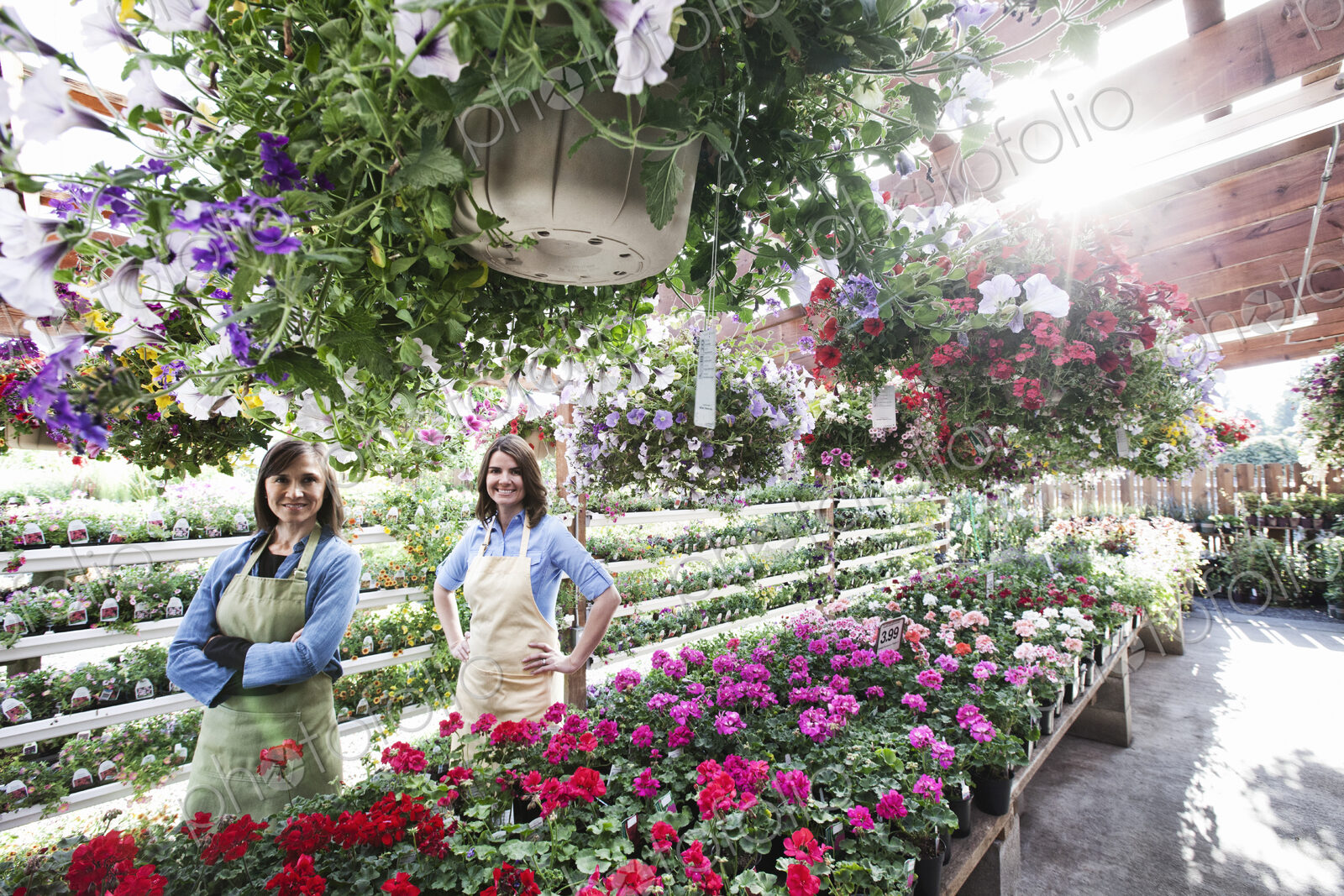 Caucasain woman owner and employee at a garden center nursery in the early morning.