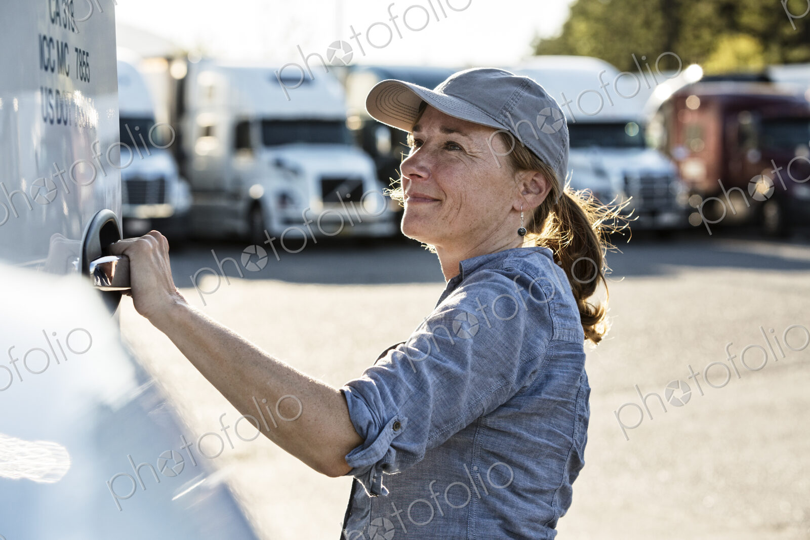 Caucasian female truck driver getting into her truck parked in a lot at a truck stop.