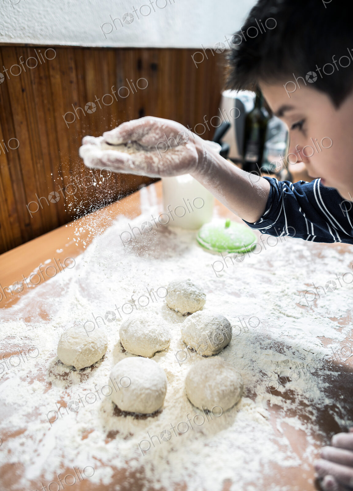 Caucasian boy sprinkling flour over dough balls