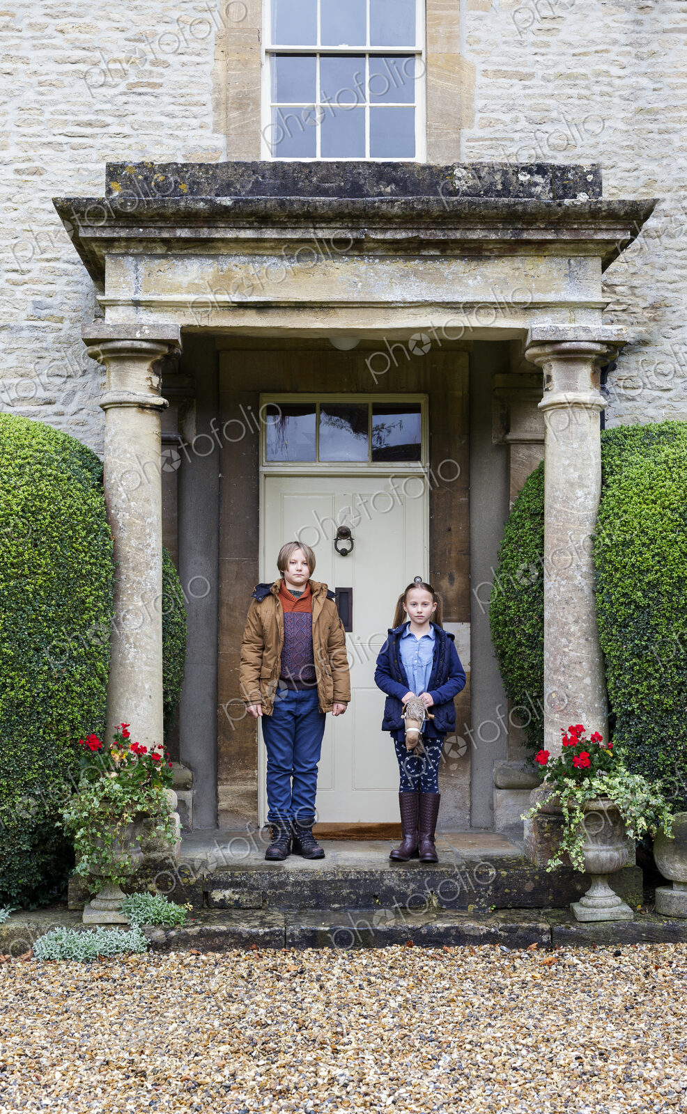 Caucasian brother and sister posing on front stoop