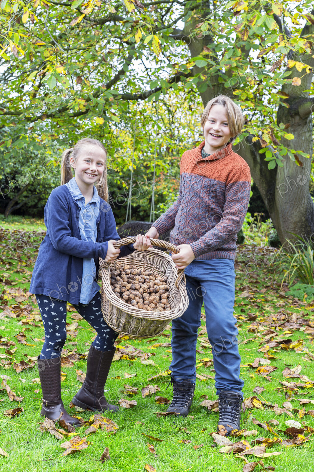 Caucasian brother and sister posing with basket of nuts