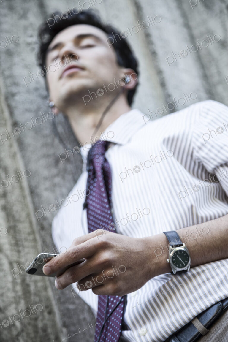 Caucasian businesman listening to music on his phone.