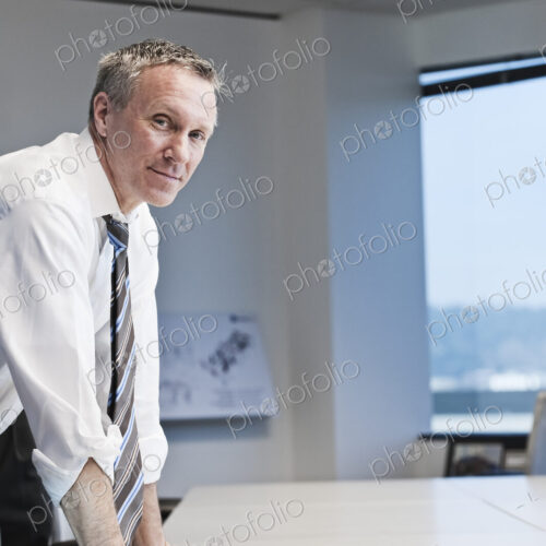 Caucasian businesman looking over paperwork at a conference room table.