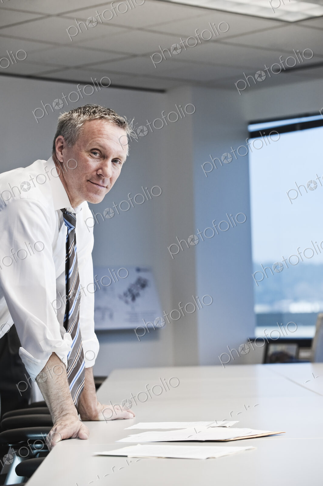Caucasian businesman looking over paperwork at a conference room table.