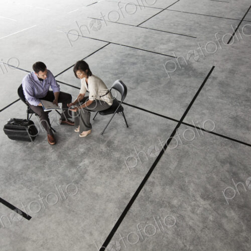 Caucasian business man and woman looking at plans for a new office layout in a large…