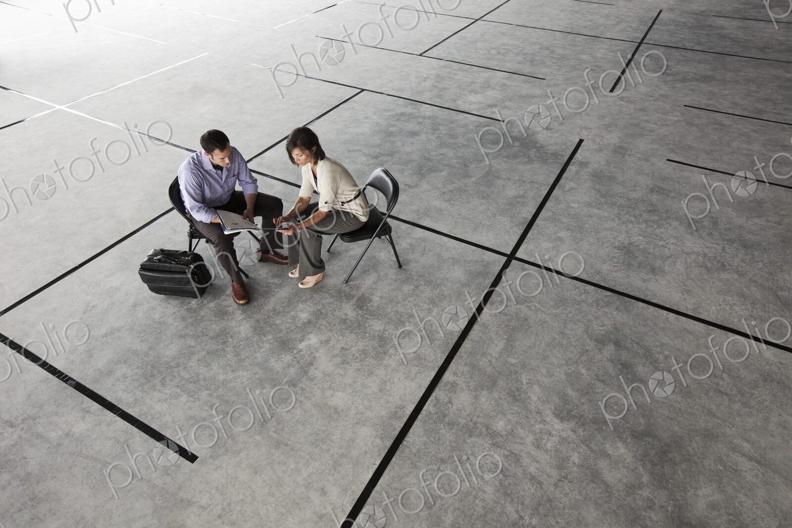Caucasian business man and woman looking at plans for a new office layout in a large…
