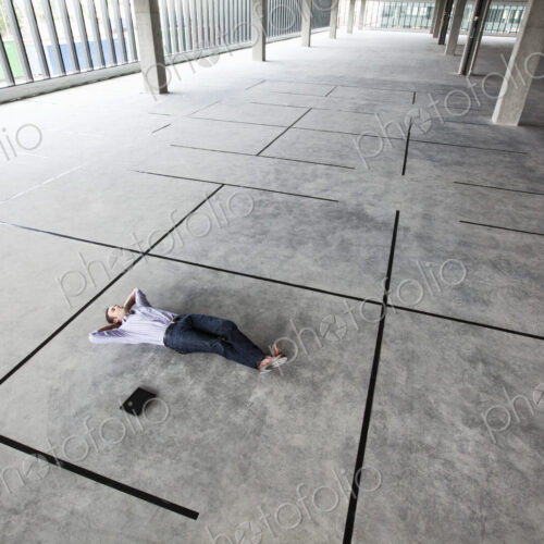 Caucasian business man relaxing in a new office layout taped to the floor of a large…