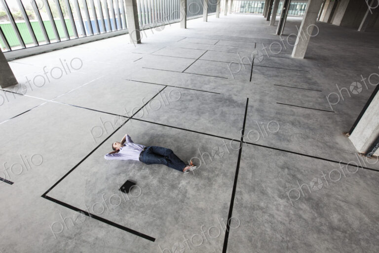 Caucasian business man relaxing in a new office layout taped to the floor of a large…