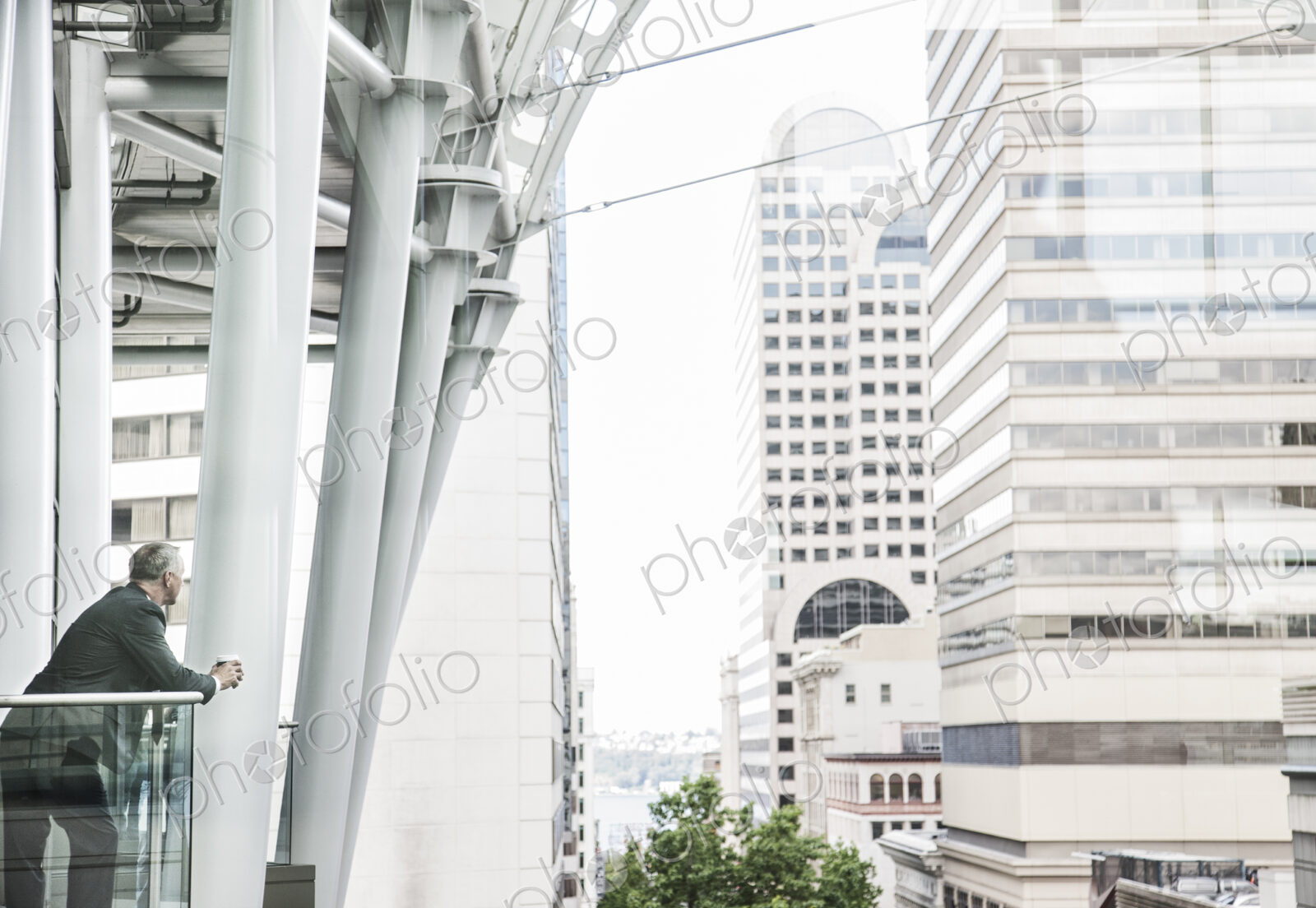 Caucasian business man standing on a balcony overlooking a cityscape.