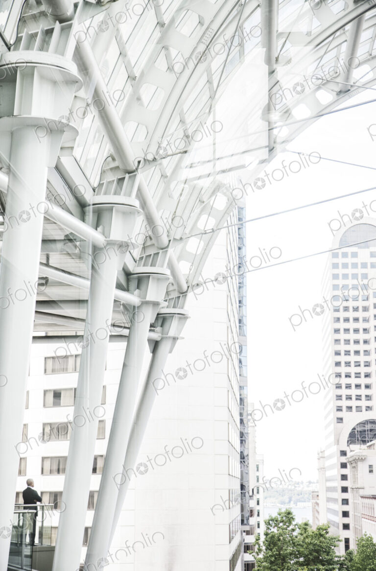 Caucasian business man standing on a balcony overlooking a cityscape.