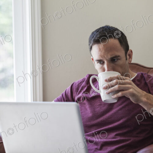Caucasian business man using a laptop for work at home in a chair. Caucasian business man using a laptop for work at home in a chair.