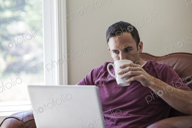 Caucasian business man using a laptop for work at home in a chair.