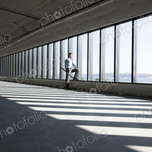 Caucasian business man with office plans standing at the windows of a new raw office…