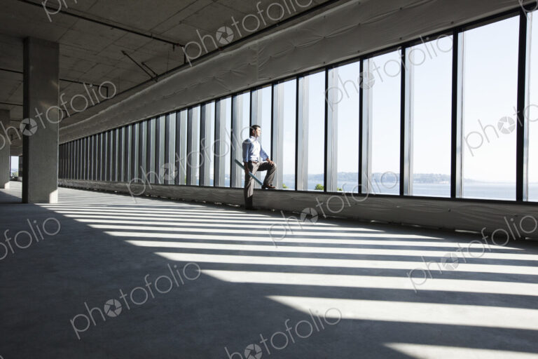 Caucasian business man with office plans standing at the windows of a new raw office…