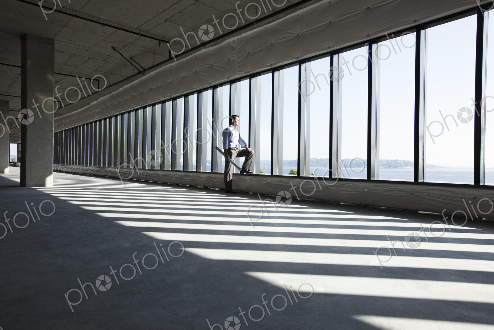 Caucasian business man with office plans standing at the windows of a new raw office…