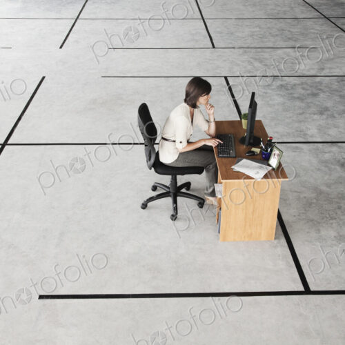 Caucasian business woman at desk looking at a new office layout in a large empty raw…