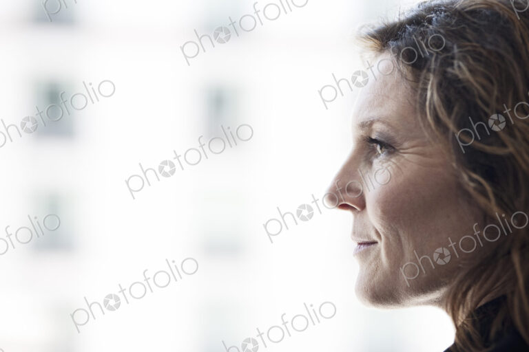 Caucasian business woman looking out the window of a conference centree lobby.