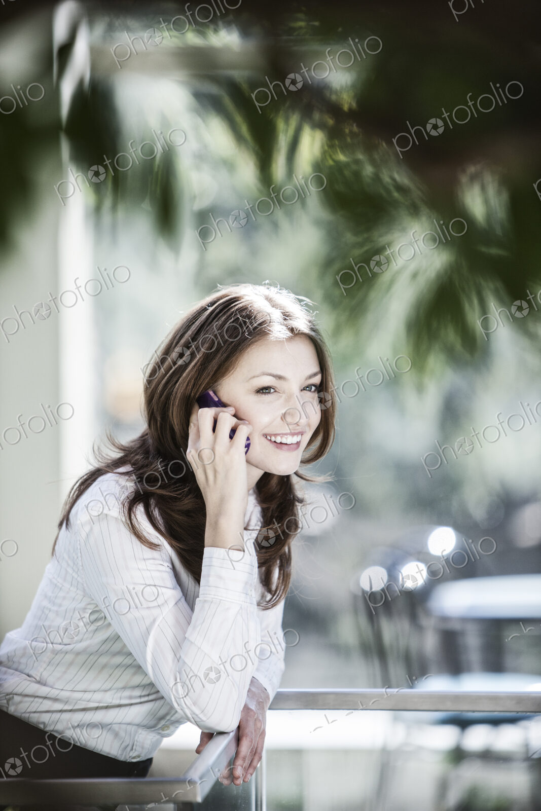 Caucasian business woman on the phone in a lobby waiting area.