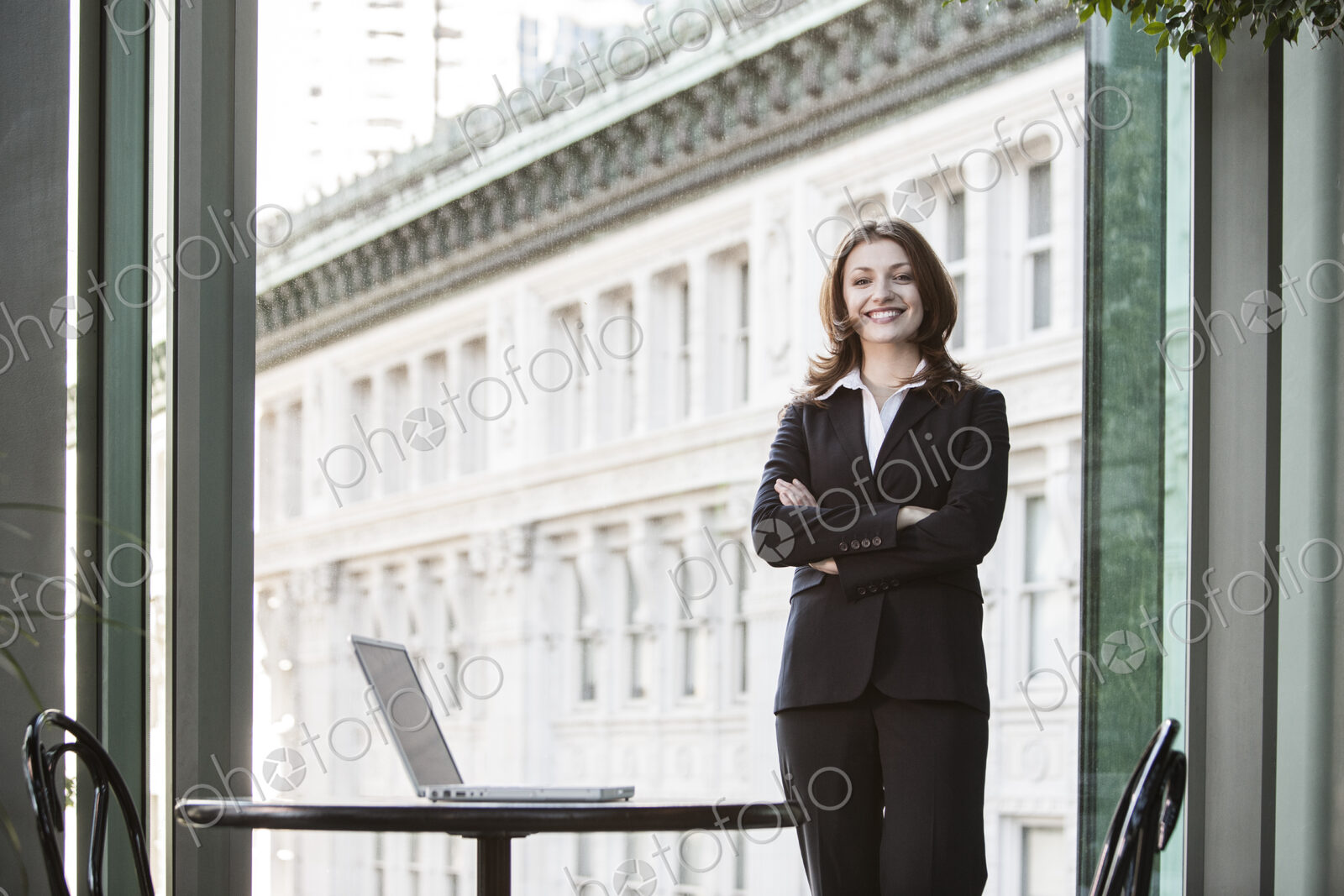 Caucasian business woman standing at a table in a lobby waiting area.