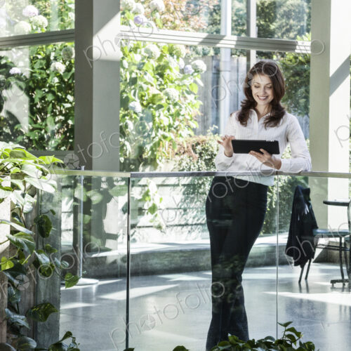 Caucasian business woman using a notebook computer in a large open lobby waiting area. Caucasian business woman using a notebook computer in a large open lobby waiting area.