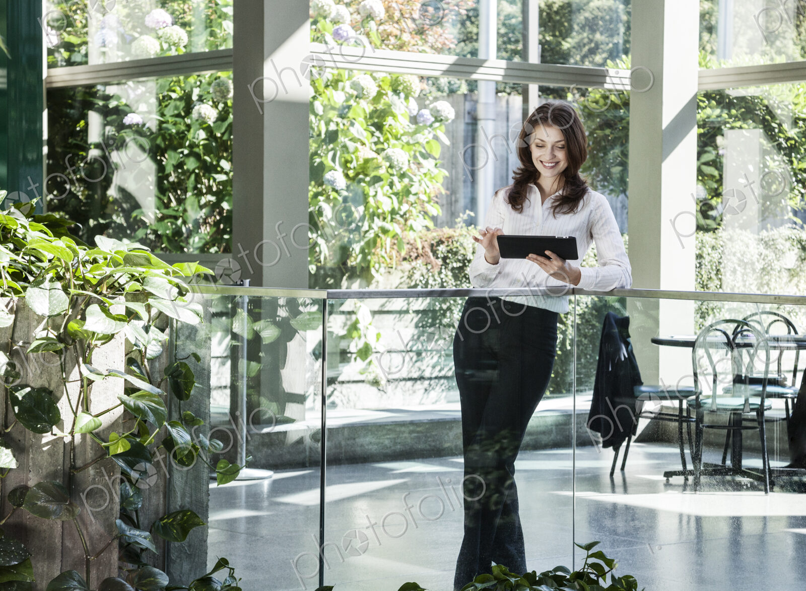 Caucasian business woman using a notebook computer in a large open lobby waiting area.