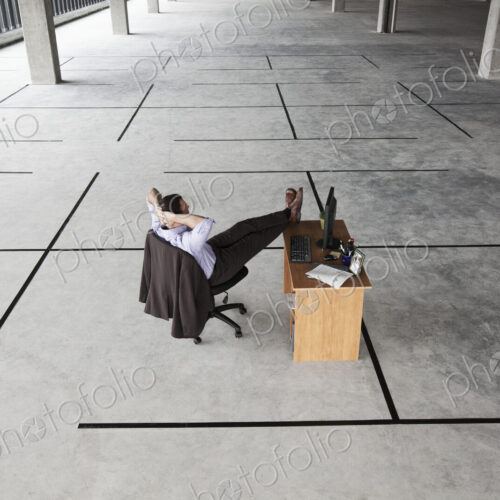 Caucasian businessman at desk looking at a new office layout in a large empty raw…