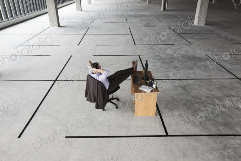 Caucasian businessman at desk looking at a new office layout in a large empty raw…