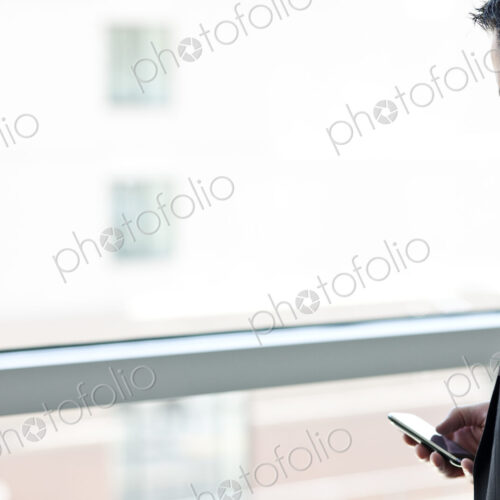 Caucasian businessman checking his cell phone in a conference centre lobby.