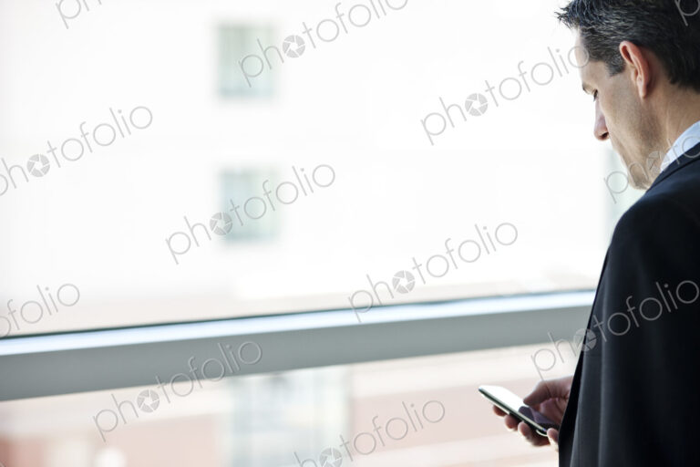 Caucasian businessman checking his cell phone in a conference centre lobby.