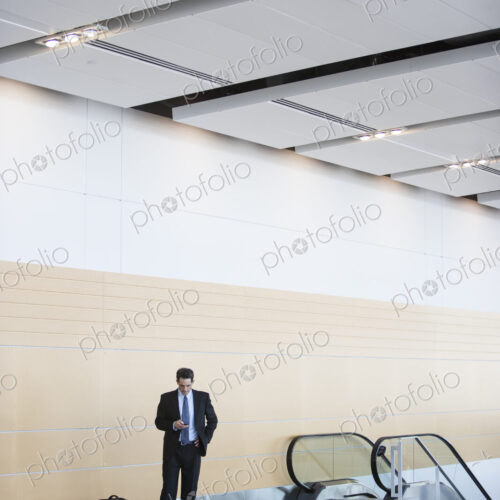 Caucasian businessman checking his cell phone in a conference centre lobby.