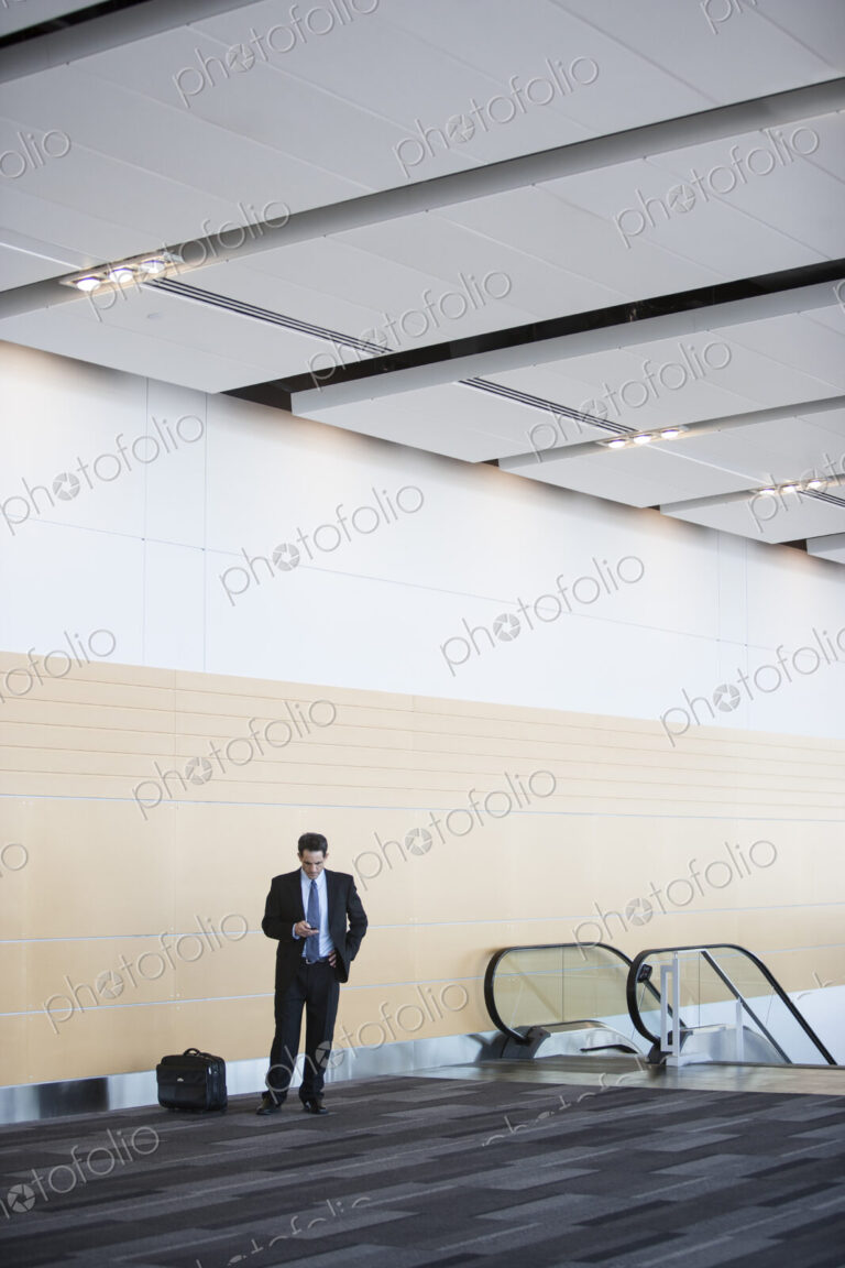Caucasian businessman checking his cell phone in a conference centre lobby.