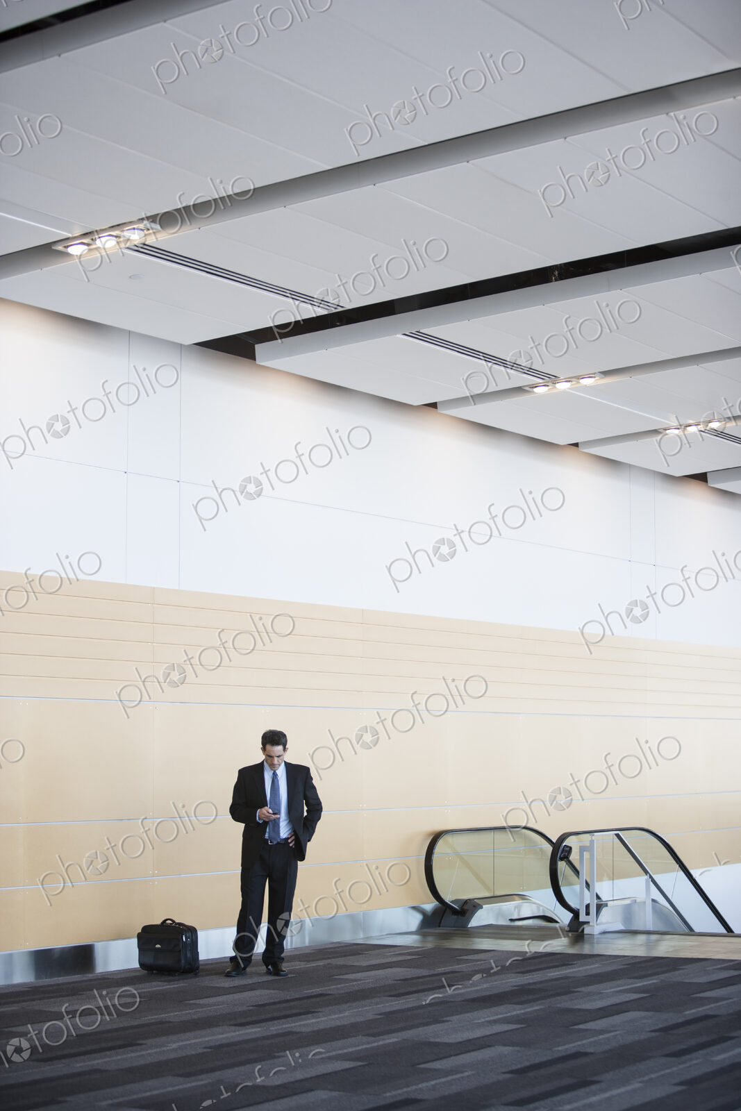 Caucasian businessman checking his cell phone in a conference centre lobby.